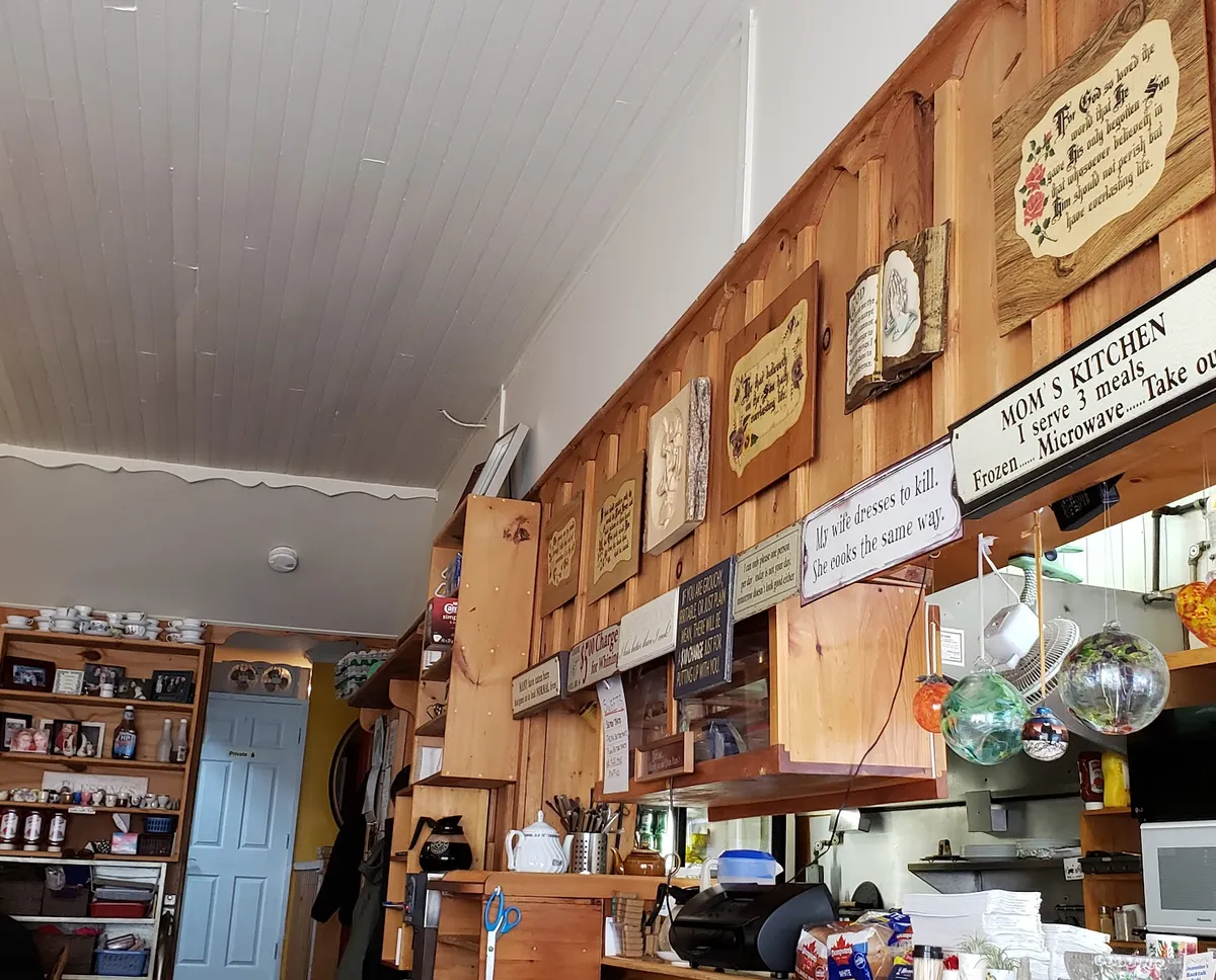 The wood-panelled counter with mugs, teapots and signs on the wall