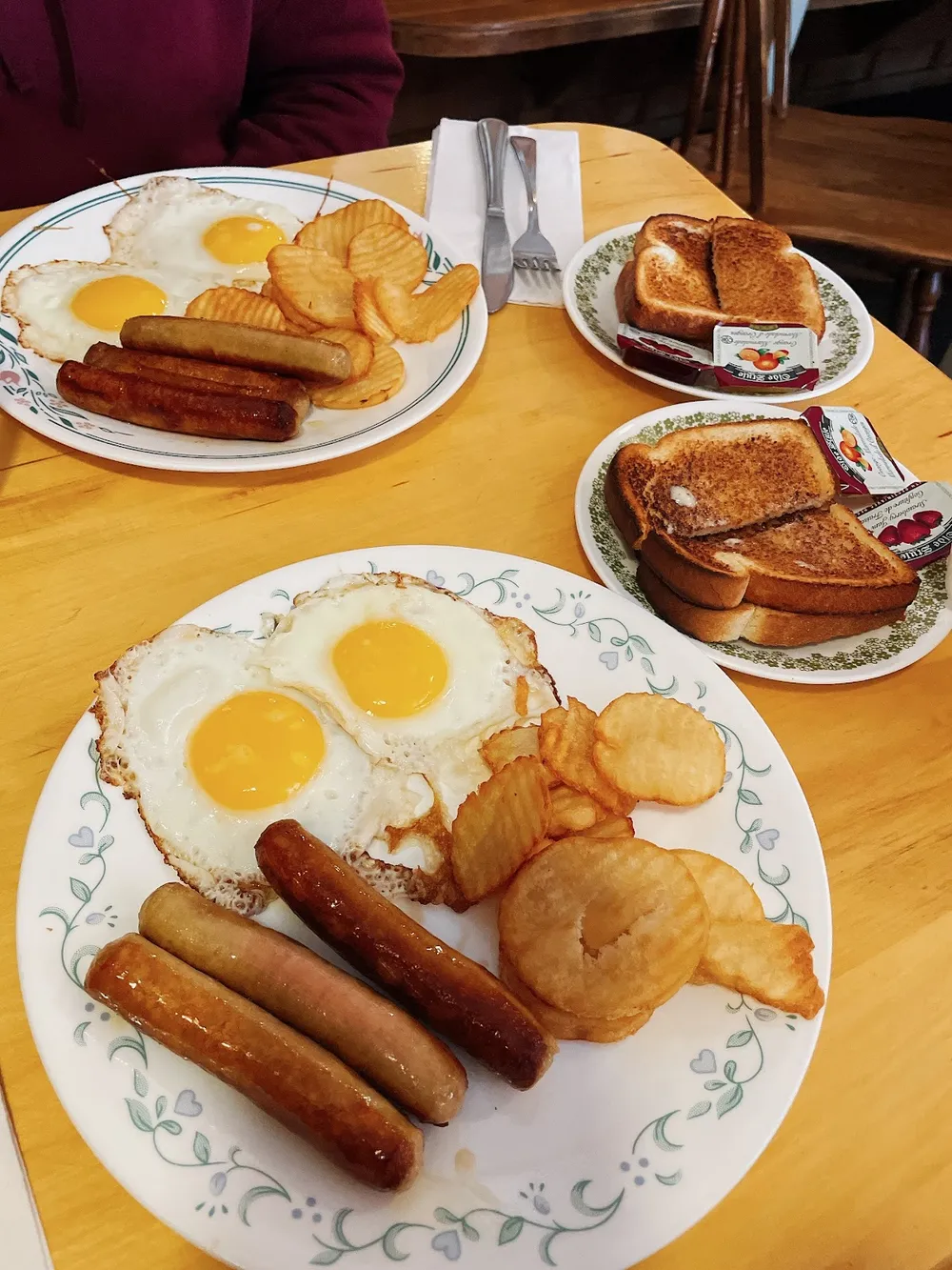 Two eggs sunny side up with sausages, home fries and toast
